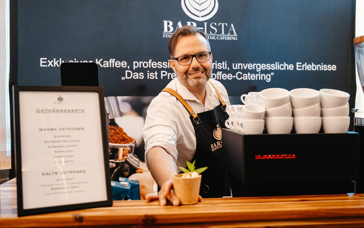 Kaffee Catering Messe Der Barista reicht ein Getränk über die Theke | Kaffee-Catering - Messe